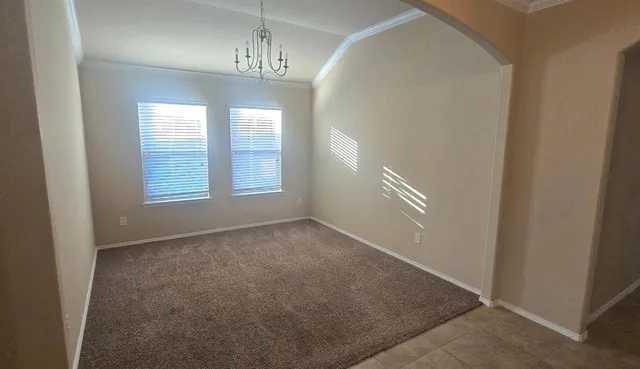 an empty room with chandelier fan and windows