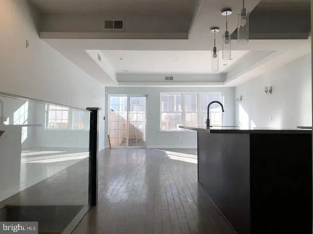 a view of an empty room with wooden floor and a ceiling fan