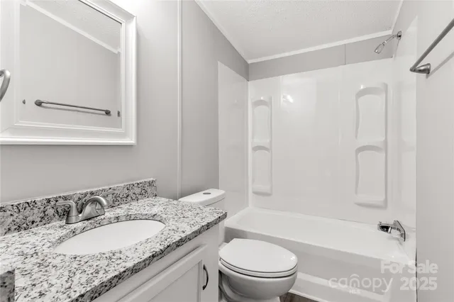 a bathroom with a granite countertop sink toilet mirror and shower