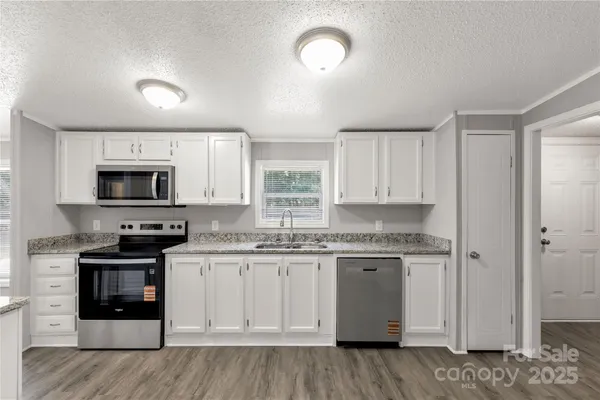a kitchen with stainless steel appliances granite countertop a stove a sink and a microwave