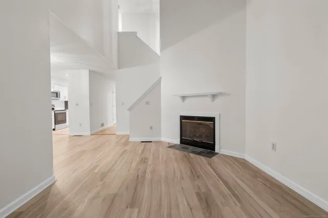 an empty room with wooden floor fireplace and windows