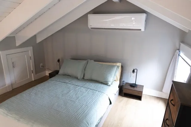 a spacious bedroom with a bed a couch and a flat tv screen on the dresser