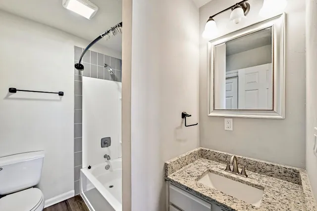 a bathroom with a granite countertop sink toilet and shower