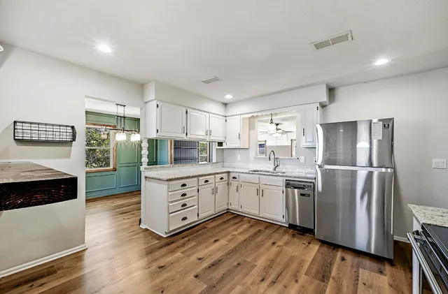 a kitchen with stainless steel appliances a refrigerator a stove a sink and white cabinets