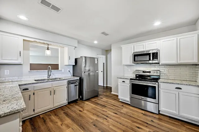 a kitchen with stainless steel appliances granite countertop a sink stove microwave and refrigerator