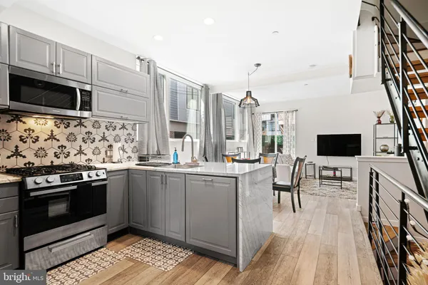 a kitchen with stainless steel appliances kitchen island granite countertop a stove top oven a sink a dining table and chairs with wooden floor