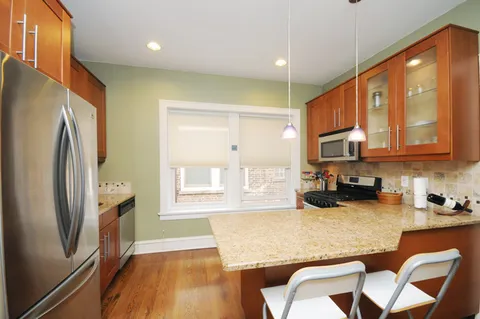 a kitchen with stainless steel appliances granite countertop a refrigerator a stove and white cabinets with wooden floor