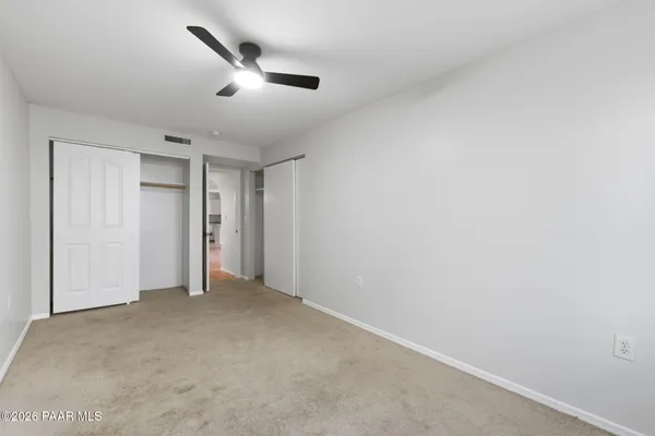 an empty room with windows and fan