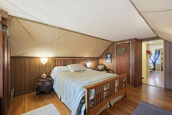 a bed sitting in a spacious bedroom next to a lamp