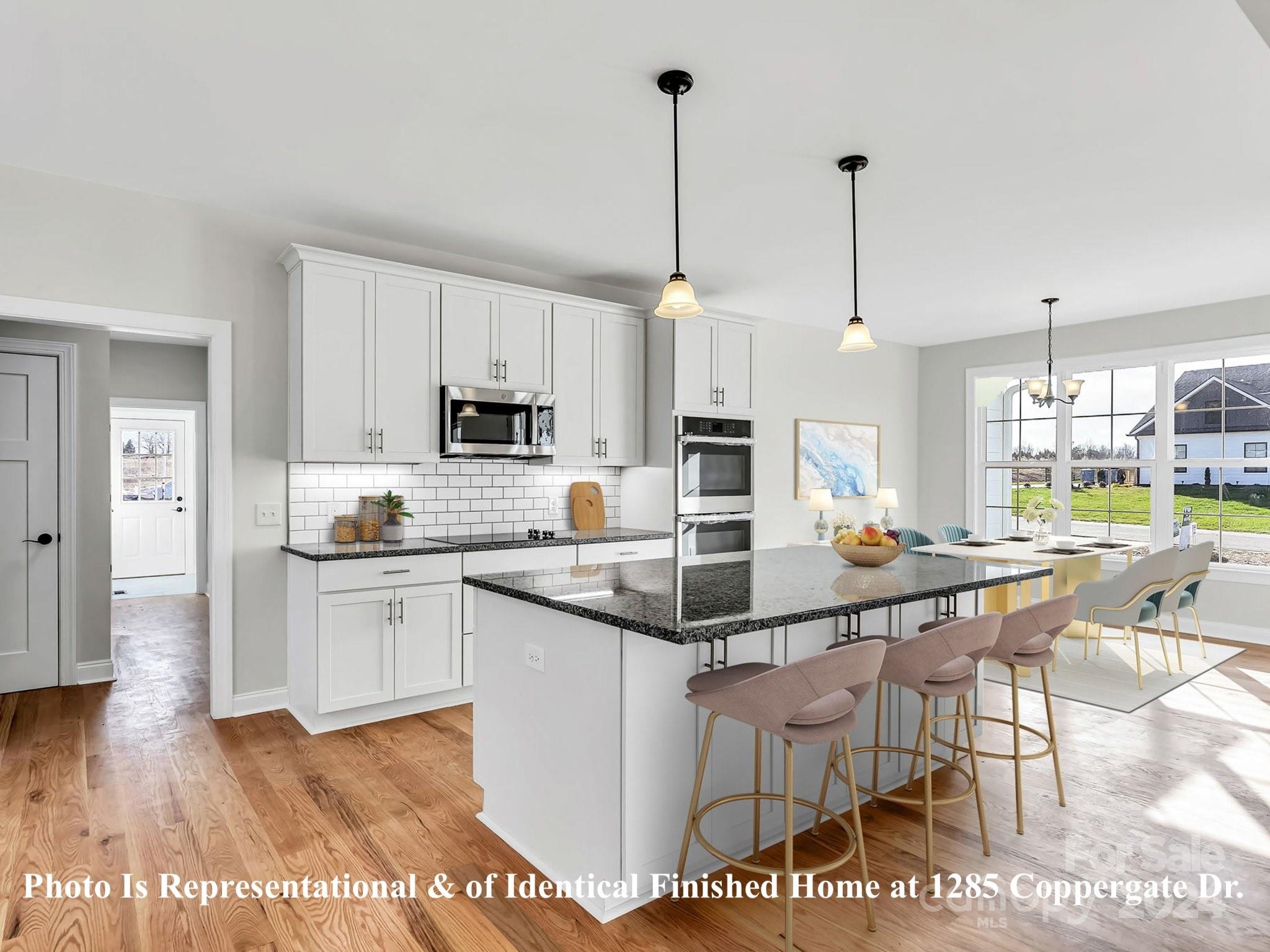 1375 Coppergate Drive Salisbury, NC 28147 - Photo 7 of 41 a kitchen with stainless steel appliances kitchen island granite countertop a sink a stove a dining table and chairs with wooden floor