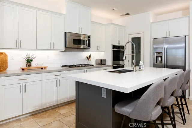 a kitchen with stainless steel appliances a stove a sink a microwave a dining table and chairs