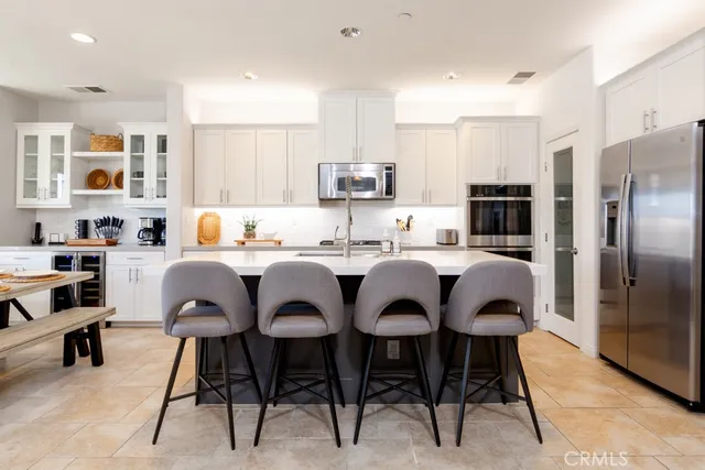 a kitchen with stainless steel appliances granite countertop a sink a stove a refrigerator and chairs