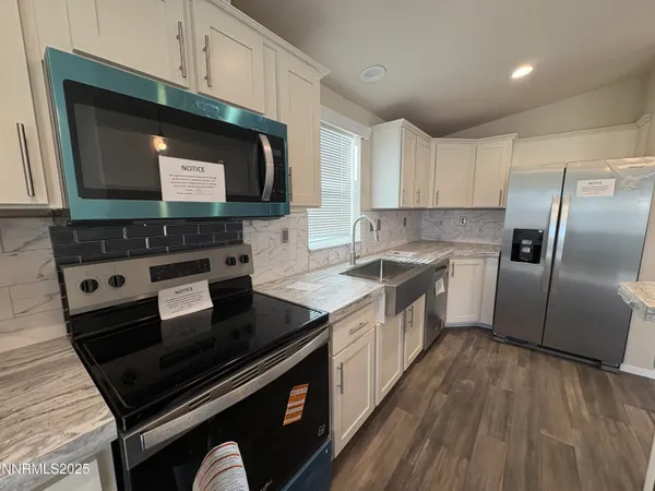 a kitchen with stainless steel appliances wooden cabinets a stove a sink and a microwave