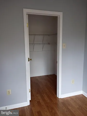 a view of an empty room with wooden floor and closet