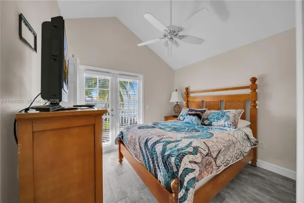 a bedroom with a bed and dresser with wooden floor