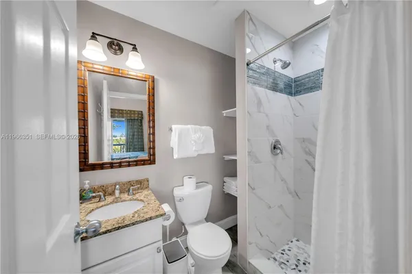 a bathroom with a granite countertop sink toilet and shower