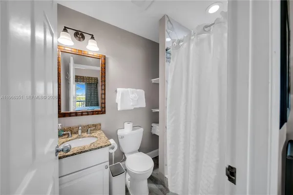 a bathroom with a granite countertop sink toilet and shower