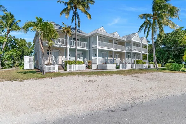 a view of a white house with a yard and palm trees