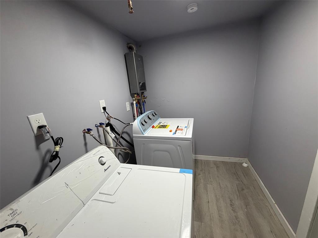 714 Southwest Dallas Street Grand Prairie, TX 75051 - Photo 26 of 27 Dedicated utility space featuring a wall-mounted tankless water heater, wood-finish flooring, and light gray wall paint