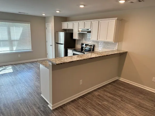 a kitchen with stainless steel appliances granite countertop a sink a stove a refrigerator and cabinets