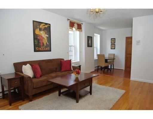 32 Fleet Street, Unit 5 Boston, MA 02113 - Photo 1 of 12 a living room with furniture a dining table and paintings on the wall with wooden floor