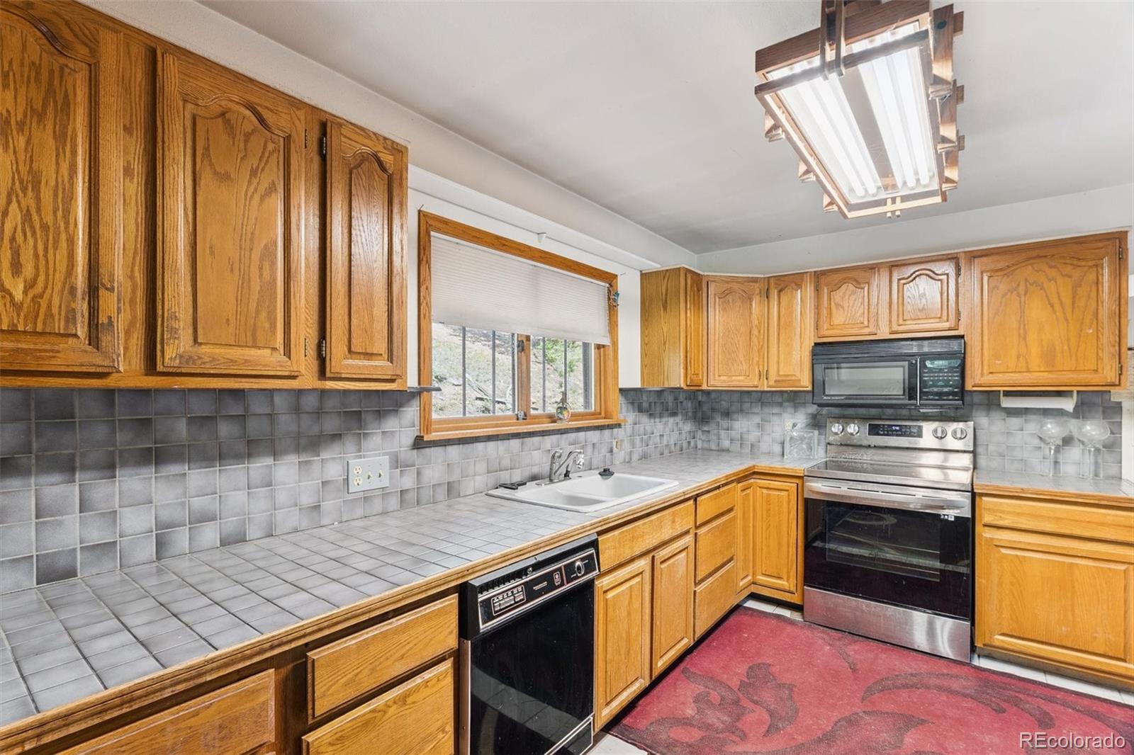 3909 County Road 72 Bailey, CO 80421 - Photo 7 of 50 a kitchen with stainless steel appliances granite countertop wooden cabinets a sink and dishwasher a stove top oven with wooden floor