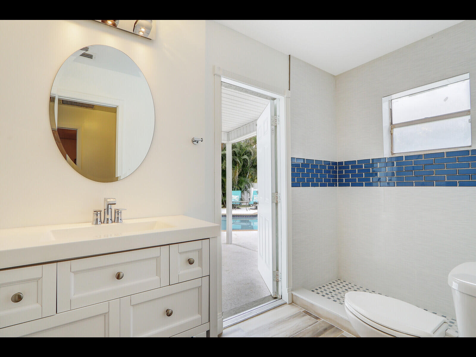 609 Oak Terrace Jupiter, FL 33458 - Photo 18 of 28 a bathroom with a sink a mirror a toilet and a window