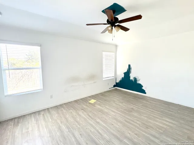 a view of empty room with wooden floor and fan
