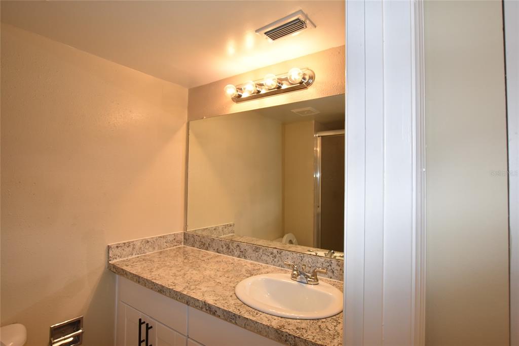 5323 Indian Creek Drive, Unit D Orlando, FL 32811 - Photo 16 of 23 a bathroom with a granite countertop sink and a mirror