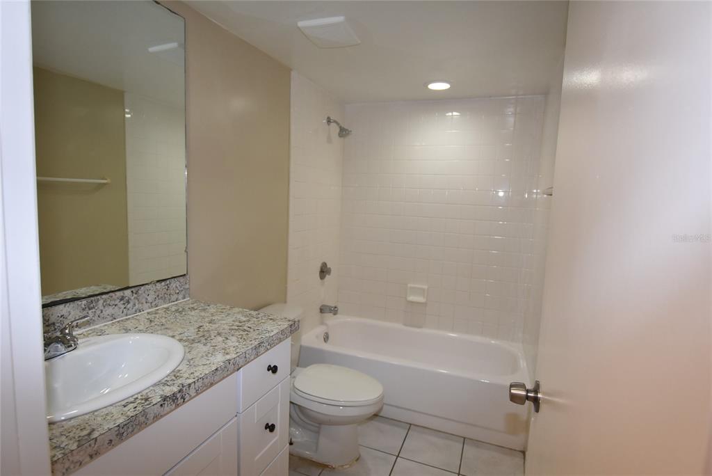 5323 Indian Creek Drive, Unit D Orlando, FL 32811 - Photo 19 of 23 a bathroom with a granite countertop sink a toilet and bathtub