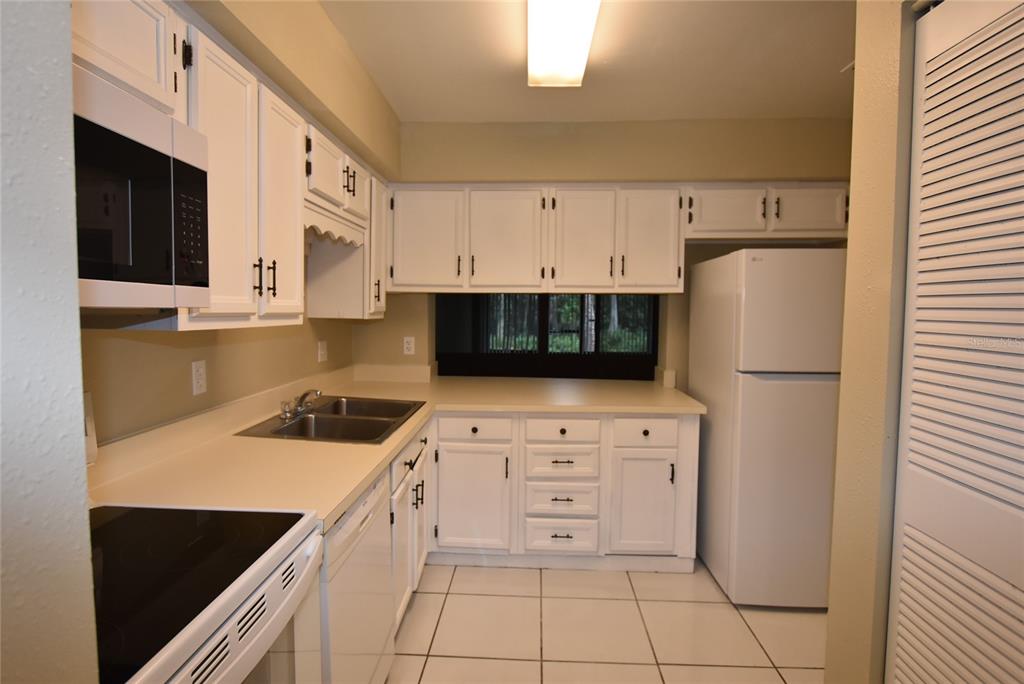 5323 Indian Creek Drive, Unit D Orlando, FL 32811 - Photo 3 of 23 a kitchen with a refrigerator stove and white cabinets