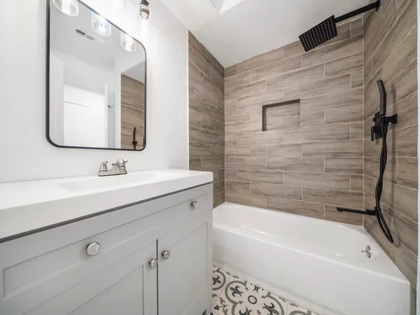 a bathroom with a tub a sink and a mirror