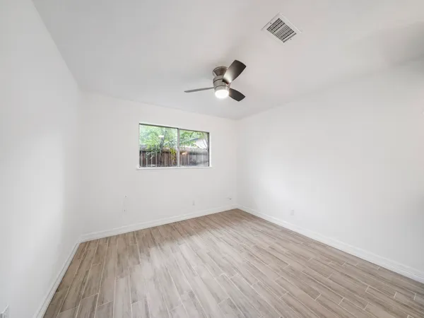 an empty room with a window and a ceiling fan