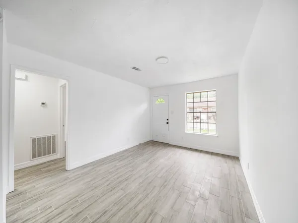 an empty room with wooden floor and windows