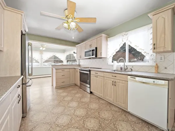 a kitchen with white cabinets and window