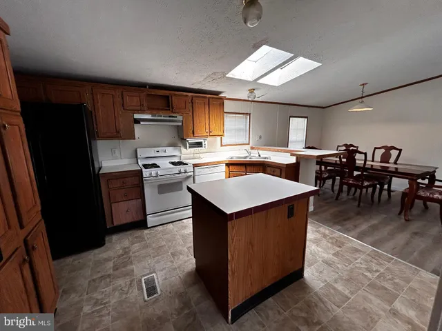 a kitchen with kitchen island a stove a sink a counter top space and cabinets