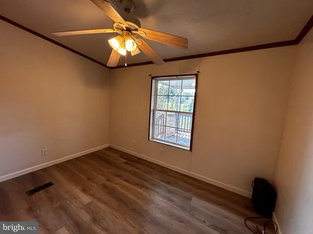 a view of an empty room with window and wooden floor