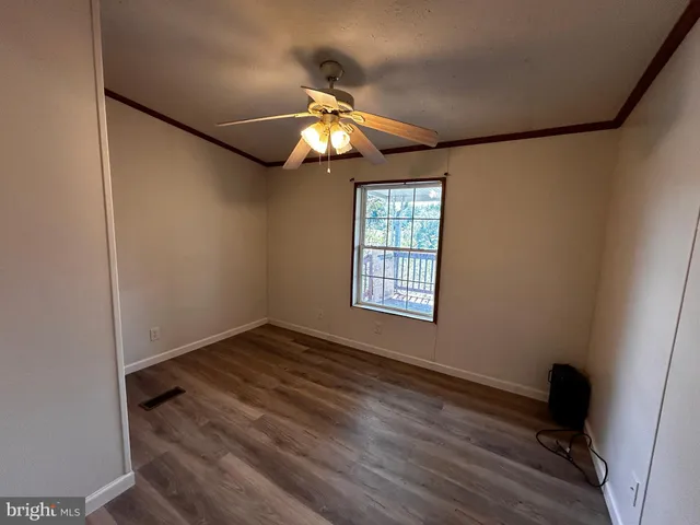 a view of an empty room with a window and wooden floor