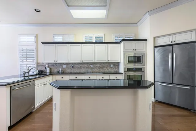 a kitchen with stainless steel appliances kitchen island granite countertop a stove and a sink