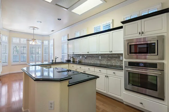 a kitchen with kitchen island granite countertop a sink stainless steel appliances and cabinets