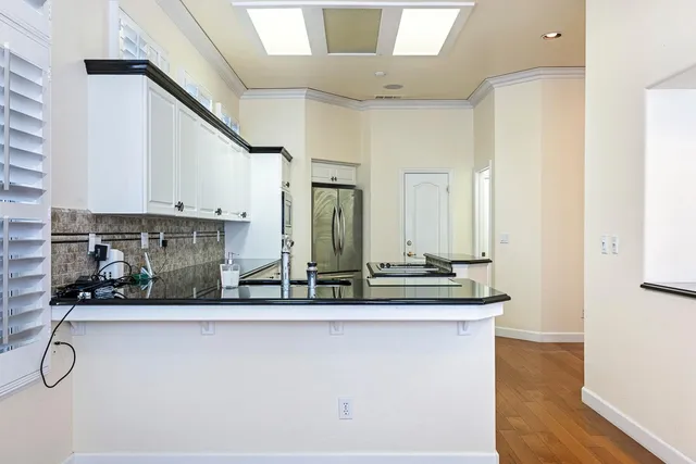 a kitchen with stainless steel appliances granite countertop a sink and a wooden floor