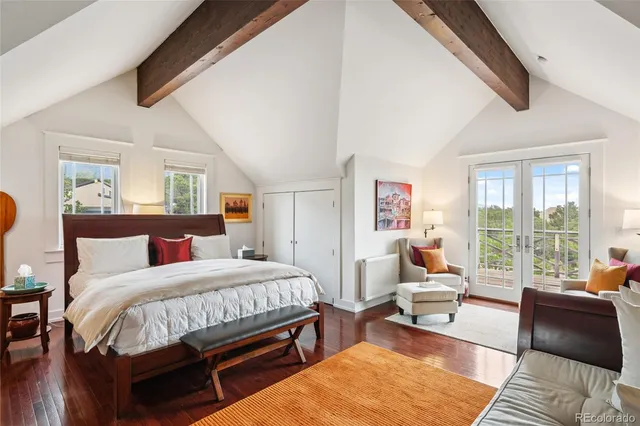 a bedroom with a bed a couch and large windows