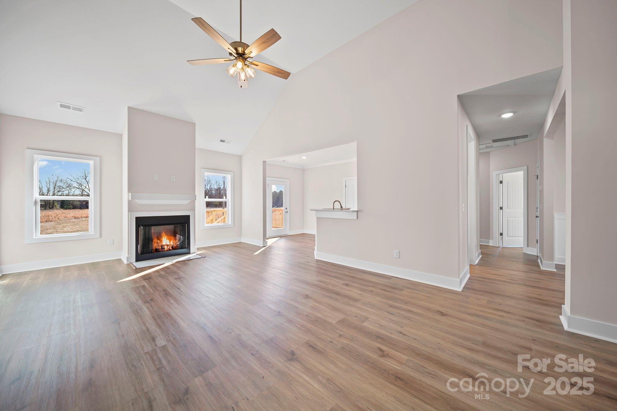 4106 New Salem Road Marshville, NC 28103 - Photo 14 of 46 an empty room with wooden floor a ceiling fan a fireplace and windows