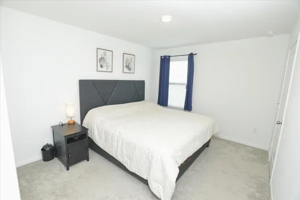a large bed sitting in a bedroom next to a lamp with window