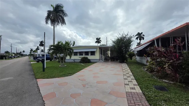 a front view of a house with a garden and trees