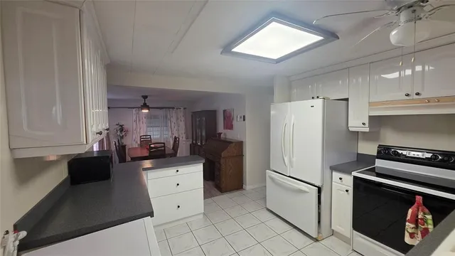 a kitchen with white cabinets and clock on the wall