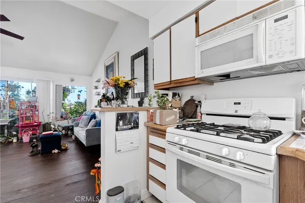 a kitchen with stove and white cabinets with wooden floor