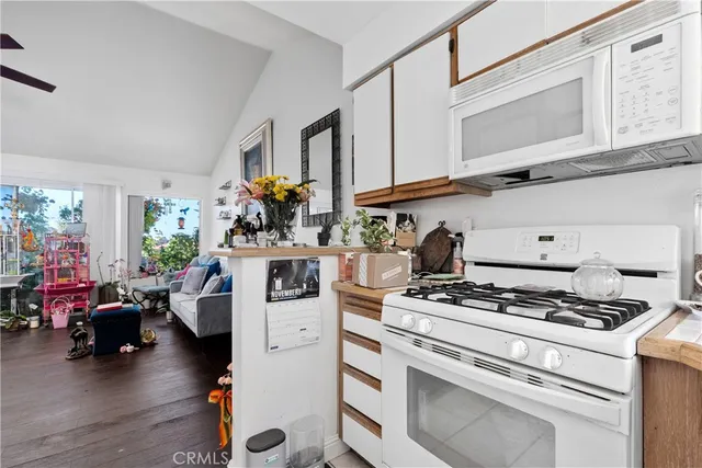 a kitchen with stove and white cabinets with wooden floor