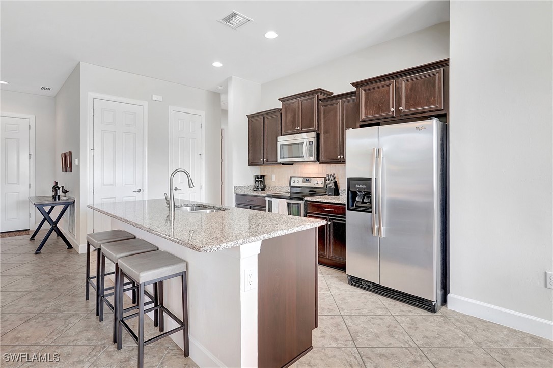 10879 Rutherford Road Fort Myers, FL 33913 - Photo 10 of 36 a kitchen with kitchen island a counter top space cabinets and stainless steel appliances