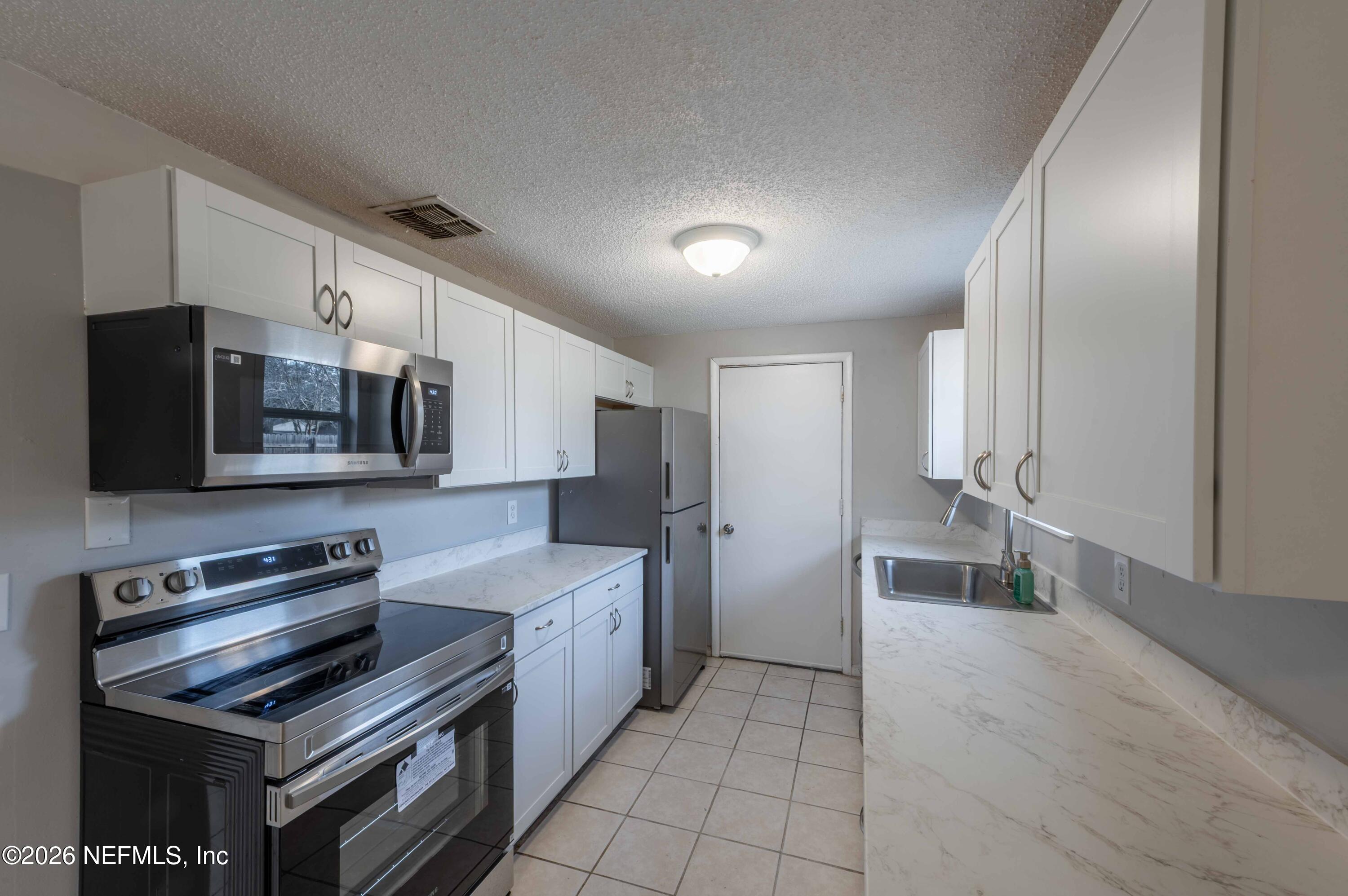 11605 Bayou Road Jacksonville, FL 32246 - Photo 23 of 39 a kitchen with stainless steel appliances a sink cabinets and a stove top oven